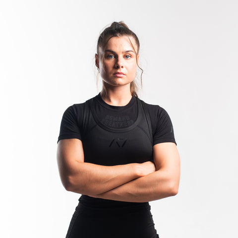Front view of woman wearing black IPF approved singlet and black A7 Meet t-shirt in stealth colourway. Black A7 logo on black material. The black A7 powerlifting singlet is made with premium materials and flatlock seams. 