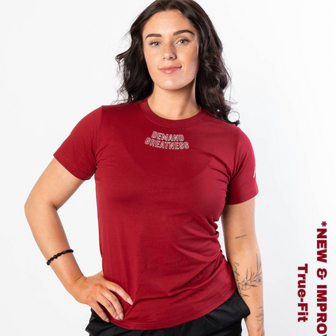 Woman wearing A7's IPF Approved Ivory rose Meet shirt. 'Demand Greatness’ written on the front of red meet t-shirt in a white double outlined font to have impact on the competition platform. Paired with black powerlifting shorts made from a stretchy squat proof material to use in strength sports training. 