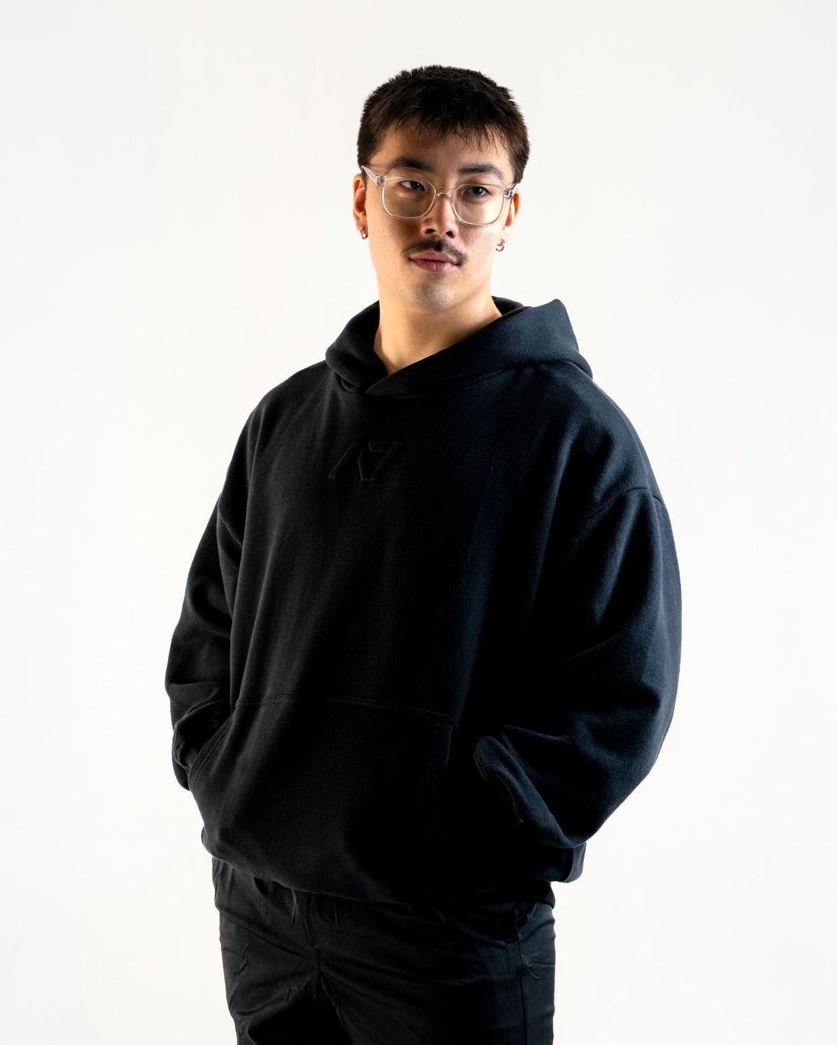 Front of the A7 Veil overfit hoodie in stealth/black. Worn by a man and unisex sizing, this strength sports apparel is meet day apparel for traveling to meets and standing on the podium 
