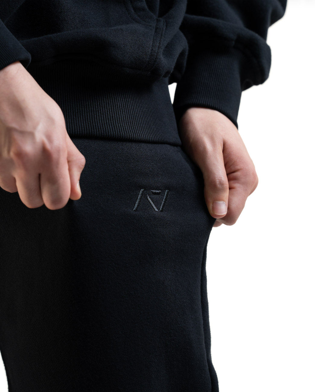 Close up of A7 Veil overfit joggers in stealth/black logo. Worn by a women and unisex sizing, this strength sports apparel is meet day apparel for traveling to meets and standing on the podium 