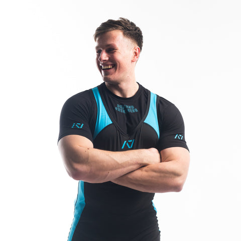Front view of Man wearing black and blue IPF approved azul singlet and azul A7 Meet t-shirt in black and blue. Blue A7 logo on black material with blue traps and side panels. The blue and black A7 powerlifting singlet is made with premium materials and flatlock seams for maximum comfort on competition platform. 