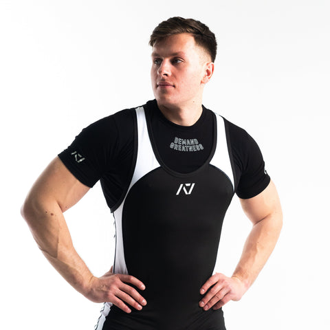 Front view of man wearing black and white IPF approved domino singlet and black A7 Meet t-shirt in black and white domino colourway. White A7 logo on black material with white straps and panels. The black A7 powerlifting singlet is made with premium materials and flatlock seams for maximum comfort on competition platform. 